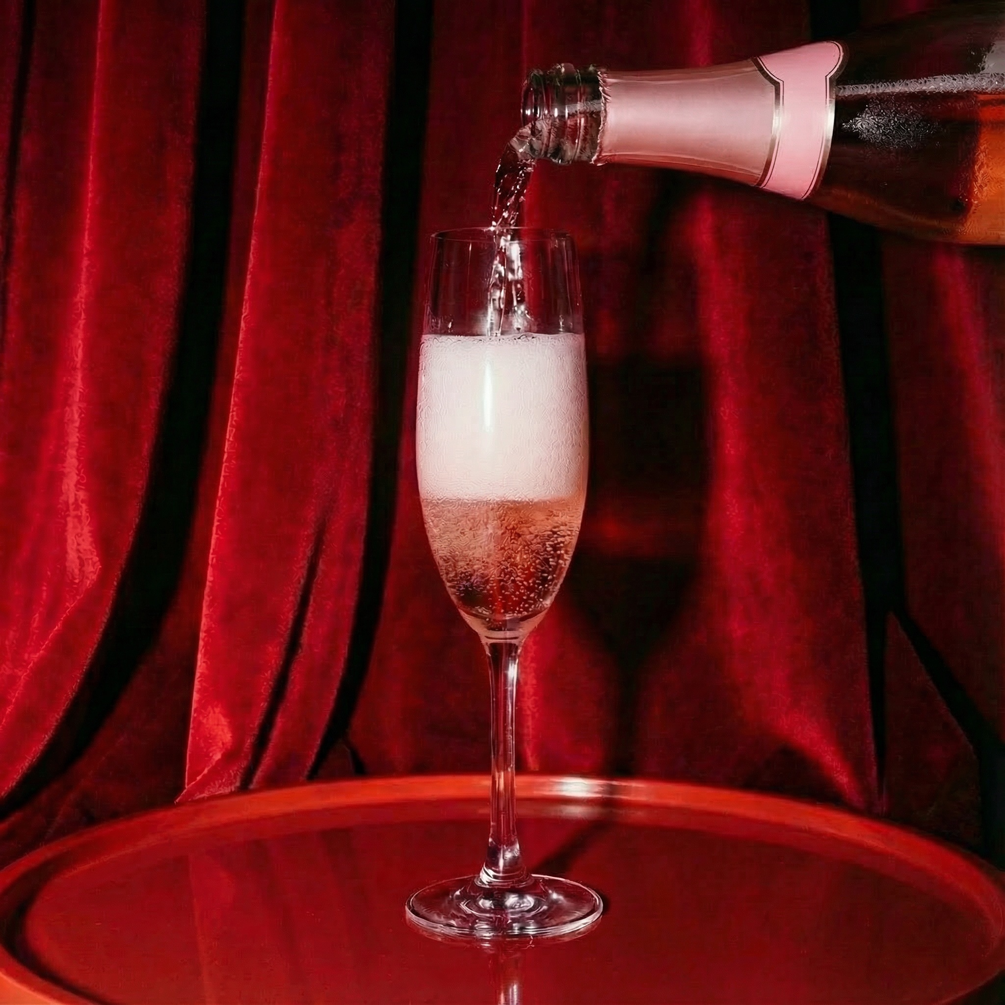 Rosé champagne being poured in a glass before the red courtains in the Sisters Janssen Suite